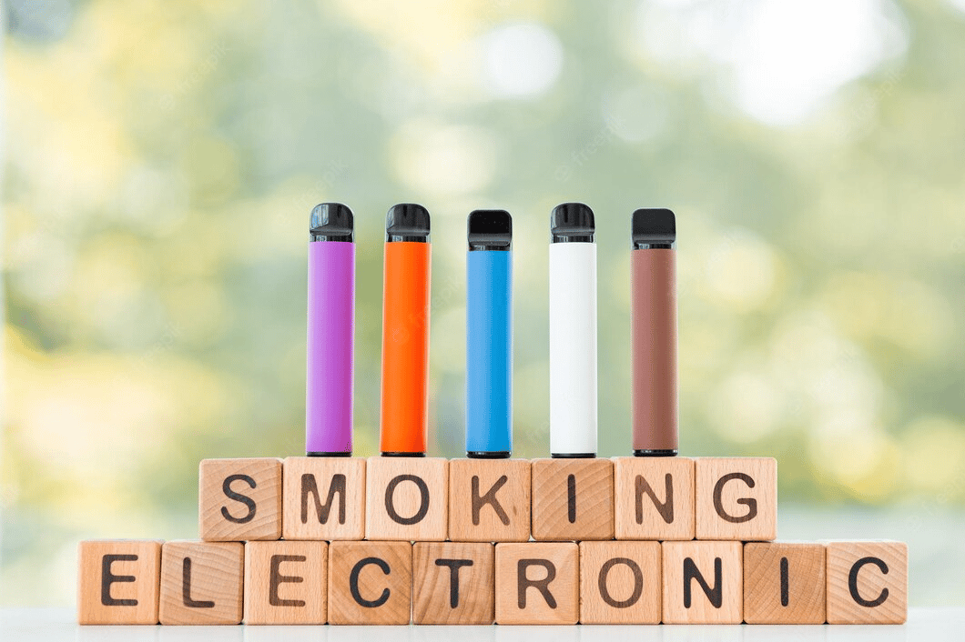 Different disposable electronic cigarettes on green summer background electronic smoking concept