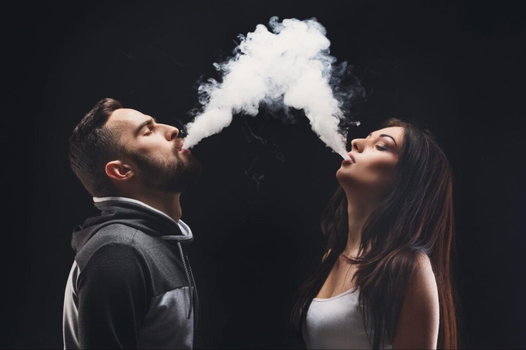 young man and woman blowing smoke